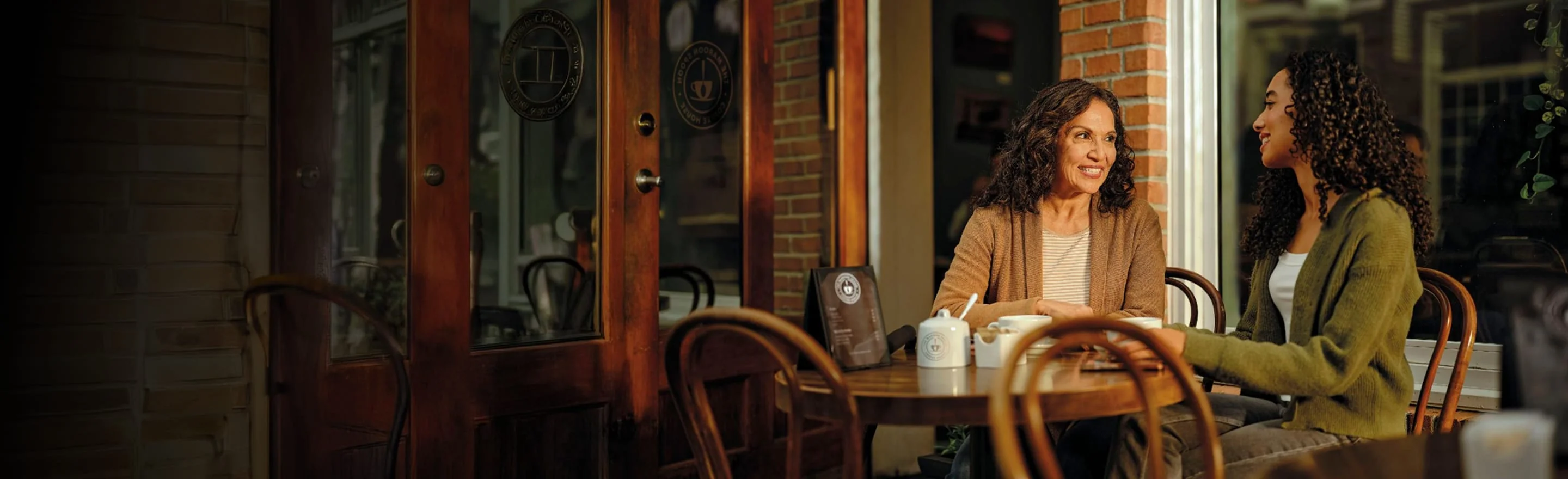 Two women talking at an outdoor café table, actor portrayal